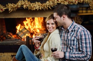 Young romantic couple sitting on sofa in front of fireplace at h