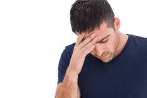 Upset man standing with his hand holding his forehead on white background