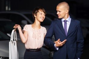 Happy young couple against a car parking