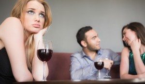 Blonde woman feeling jealous of couple flirting beside her in a bar