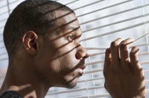 Nervous young black man looking out window, horizontal