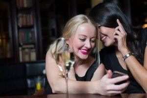 Two women on a night out using mobile phones