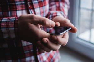 The man is using a smartphone. Modern mobile phone in hand.