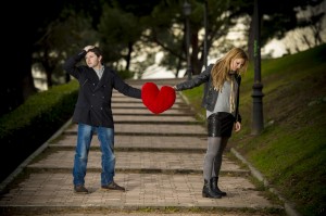 attractive couple fighting over a love heart pillow