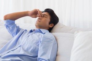 Man sitting on couch with a headache