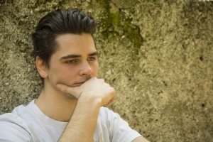 Sad young man with hand on chin thinking