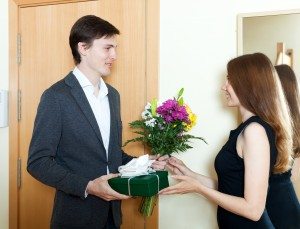 Young man giving flowers and gift to woman