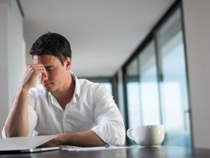 frustrated young business man working on laptop computer at home