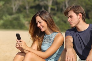 Jealous boyfriend watching his girlfriend texting on the phone