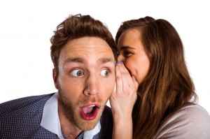 Woman whispering secret into friends ear