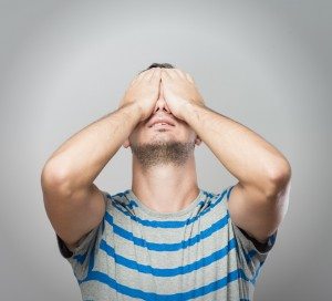 Young Caucasian man hiding his face with hand