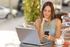 Woman working with her phone and laptop in a restaurant