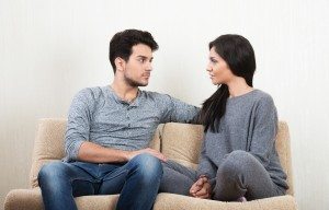 Young happy couple talking each other sitting on a sofa