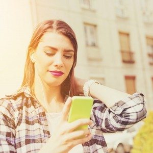 Teenage girl with smartphone texting outdoors in summer