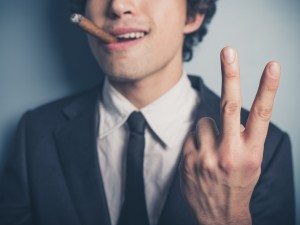 Young businessman with cigar showing rude gesture