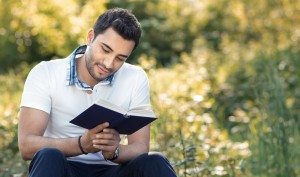 Student reading book in a park.