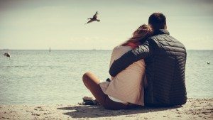 couple sitting on beach rear view