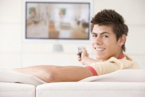 Man in living room watching television smiling