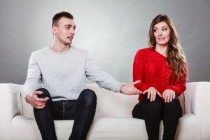 Shy woman and man sitting on sofa. First date.