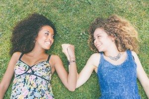 Two beautiful women lying on the grass. One is caucasian, the other is black, multicultural and friendship concepts.