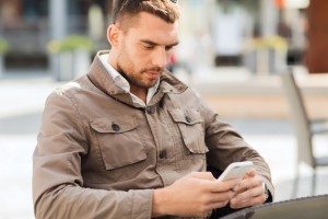 man with smartphone at city street cafe