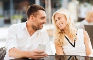 happy couple with smatphone at city street cafe