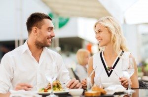 happy couple eating dinner at restaurant terrace