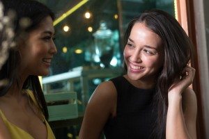 Two women sitting outdoors at night and smiling with each other