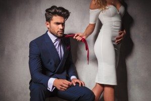 sexy blonde woman is pulling her lover by his tie