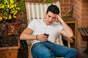 Handsome young man in balcony using cell phone